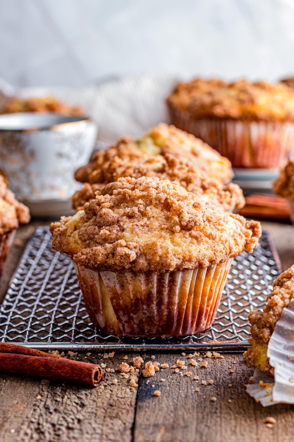 Cinnamon strusel muffin on a cooling rack on wood table.