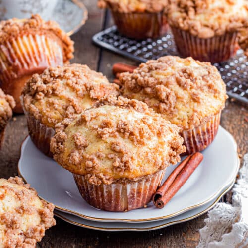 3 Cinnamon streusel muffins on a plate with a cinnamon stick.