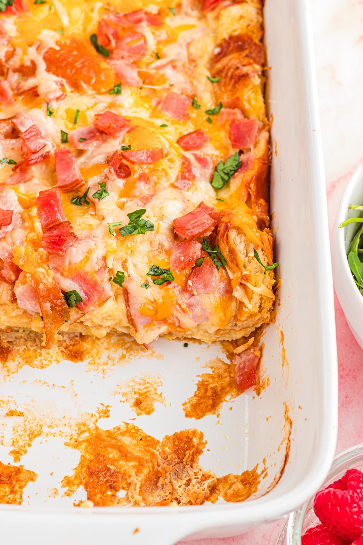 Casserole dish with piece missing of ham and cheese croissant bake.