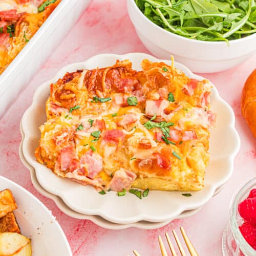 Ham and Cheese Croissant Bake on table with roast potatoes arugula salad and berries.