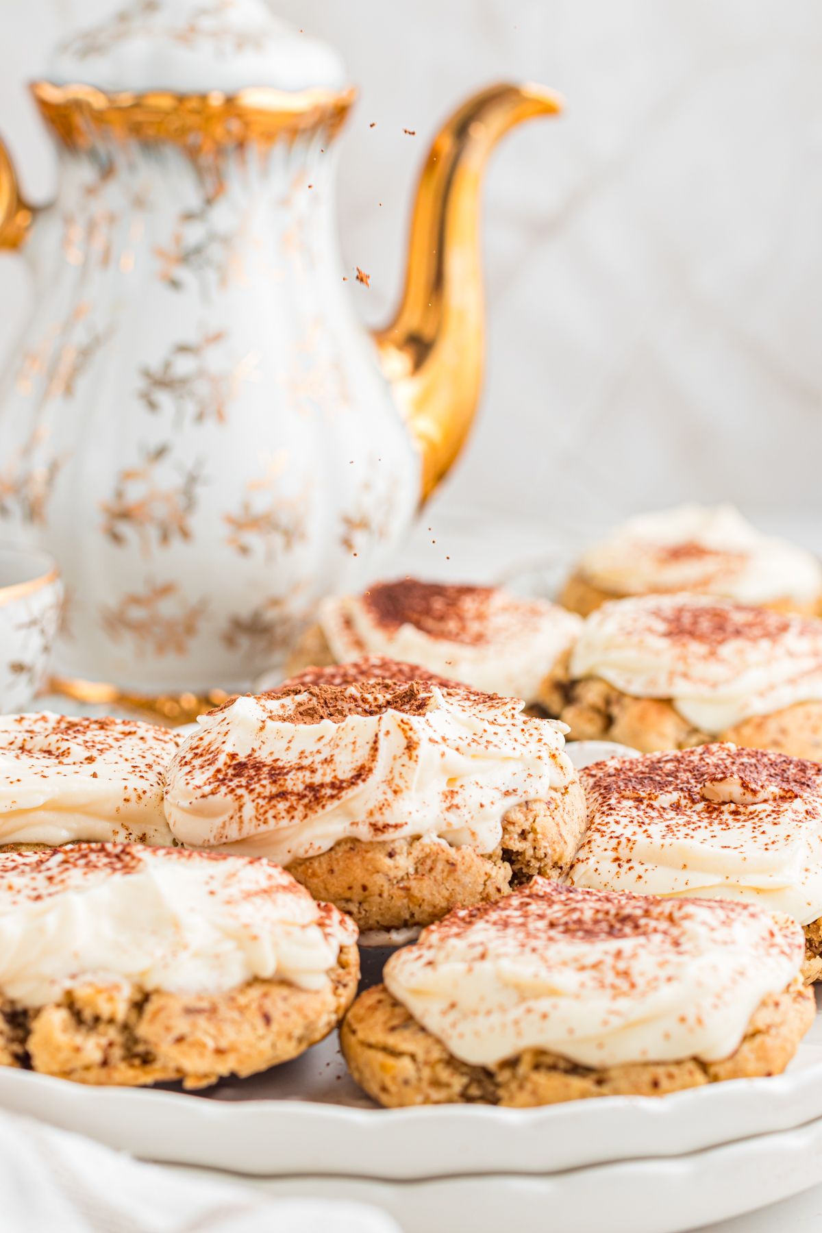 Tiramisu cookies on plate with pretty coffee pot in the background.