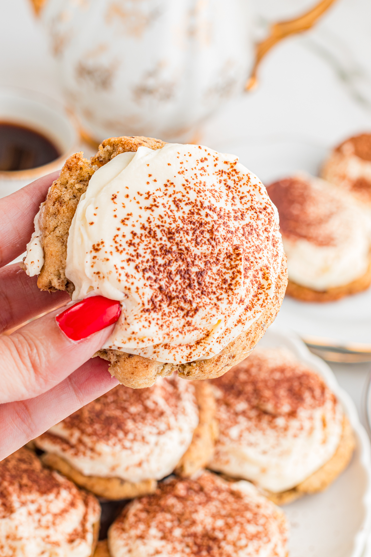 Hand with red finger nail holding a tiramisu cookie.